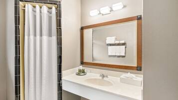 A bathroom with a white sink, mirror, and shower curtain.