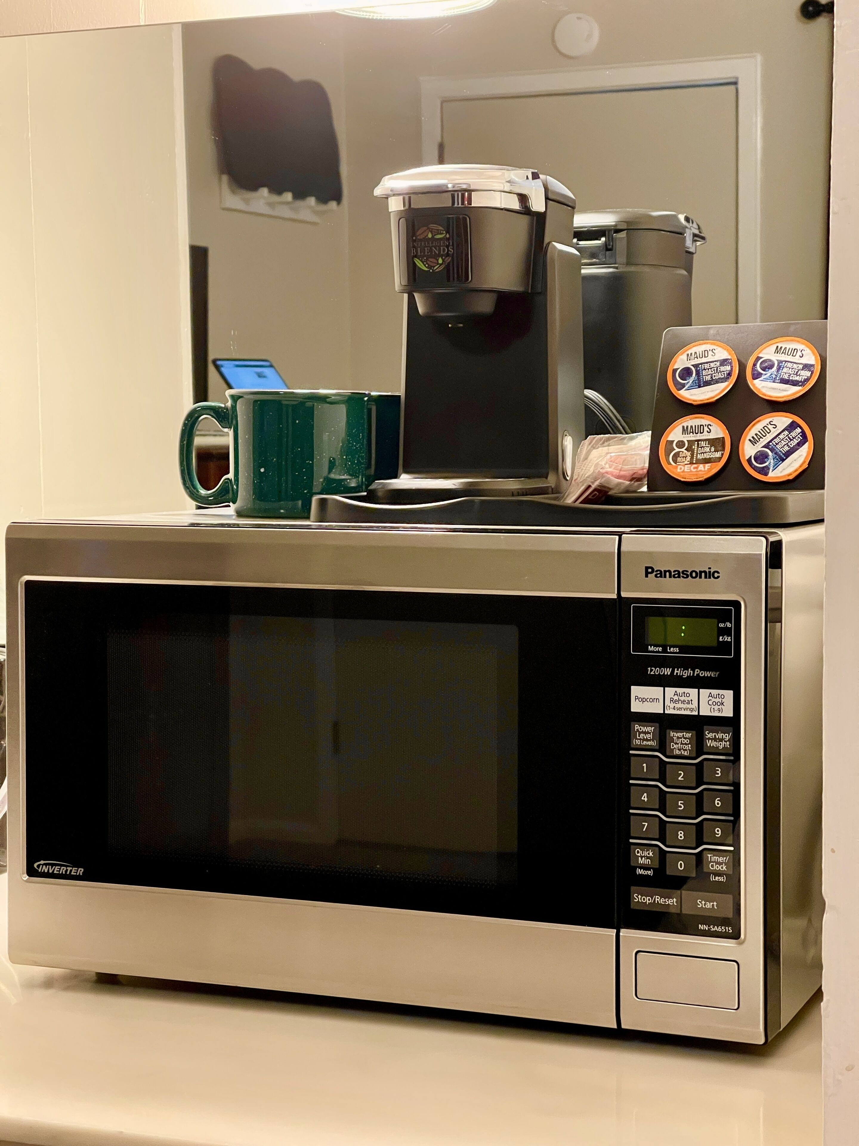 A Panasonic microwave oven with a coffee maker and Maud's coffee pods on top.