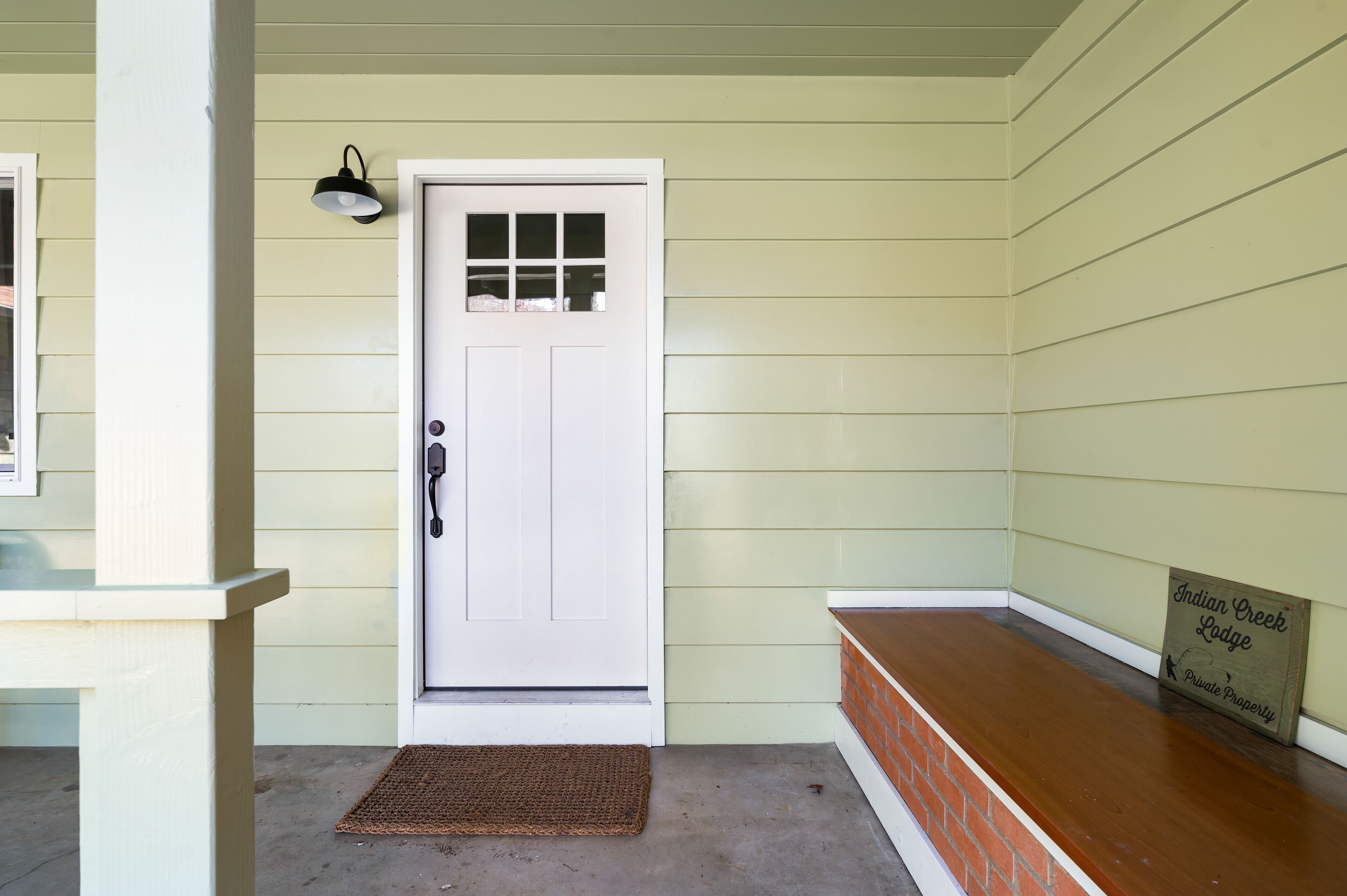 A white door with a small window, a black wall-mounted light, and a 'Private Property' sign.