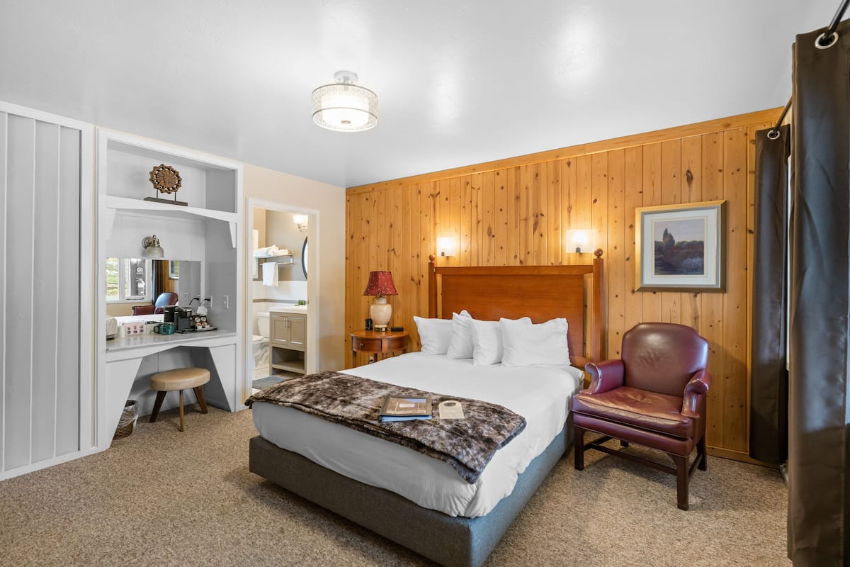 Une chambre à coucher comprenant un lit, un bureau, une chaise et un panneau mural en bois.