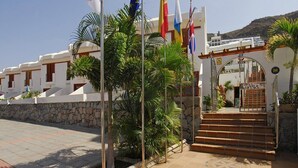Un edificio con varias banderas, un muro de piedra y una escalera que conduce a una entrada.