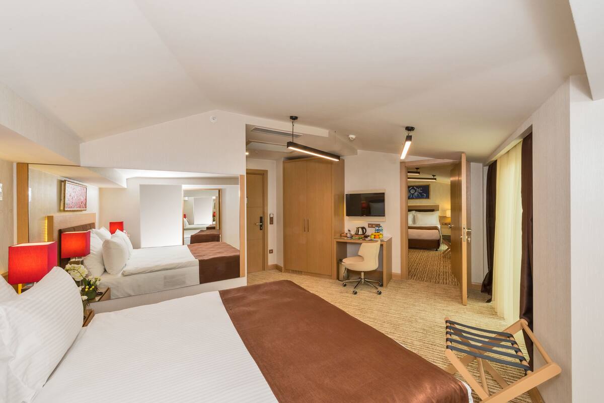 Ein Hotelzimmer mit einem großen Bett, einem Schreibtisch, einem Sessel und einem Fernseher.