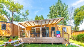 Una cabaña de madera con un porche cubierto, mesa de picnic y zona de estar al aire libre.