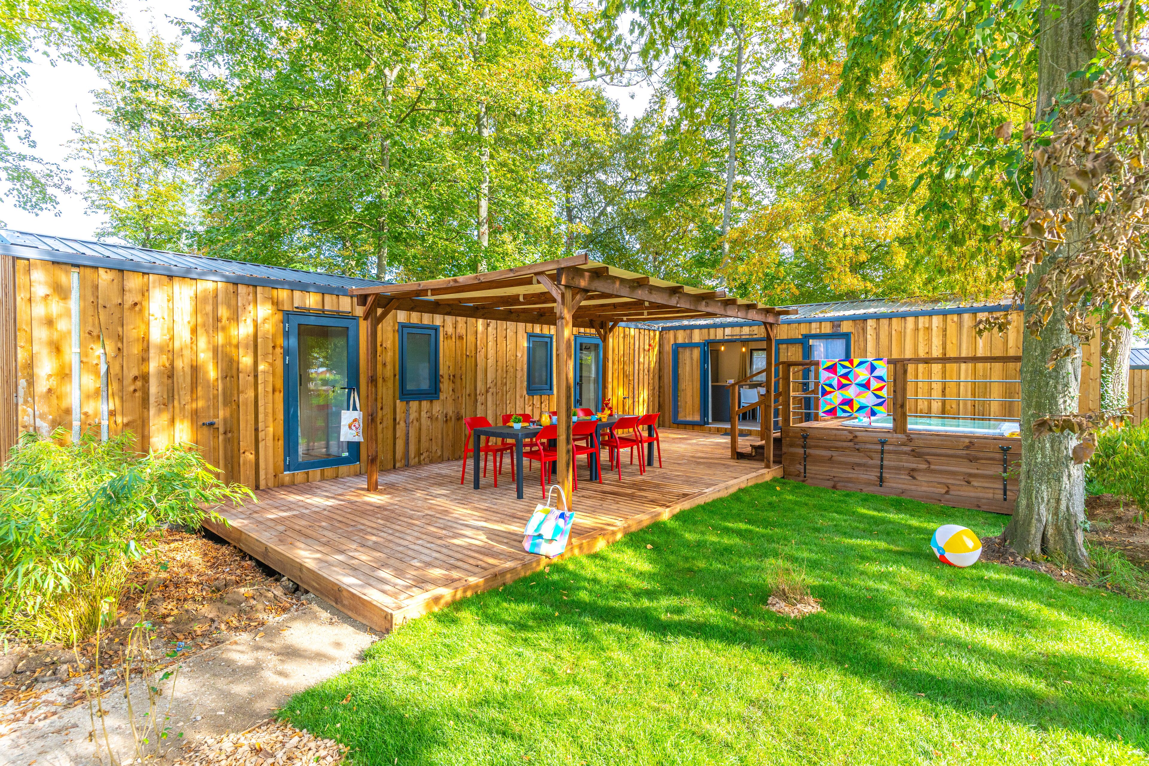 Una cabaña de madera con un porche, mobiliario exterior y una pequeña piscina.