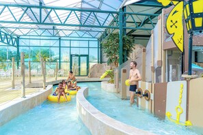 An indoor water park with a glass ceiling, a pool, and play structures. - Camping Le Parc de Paris (Villevaude)