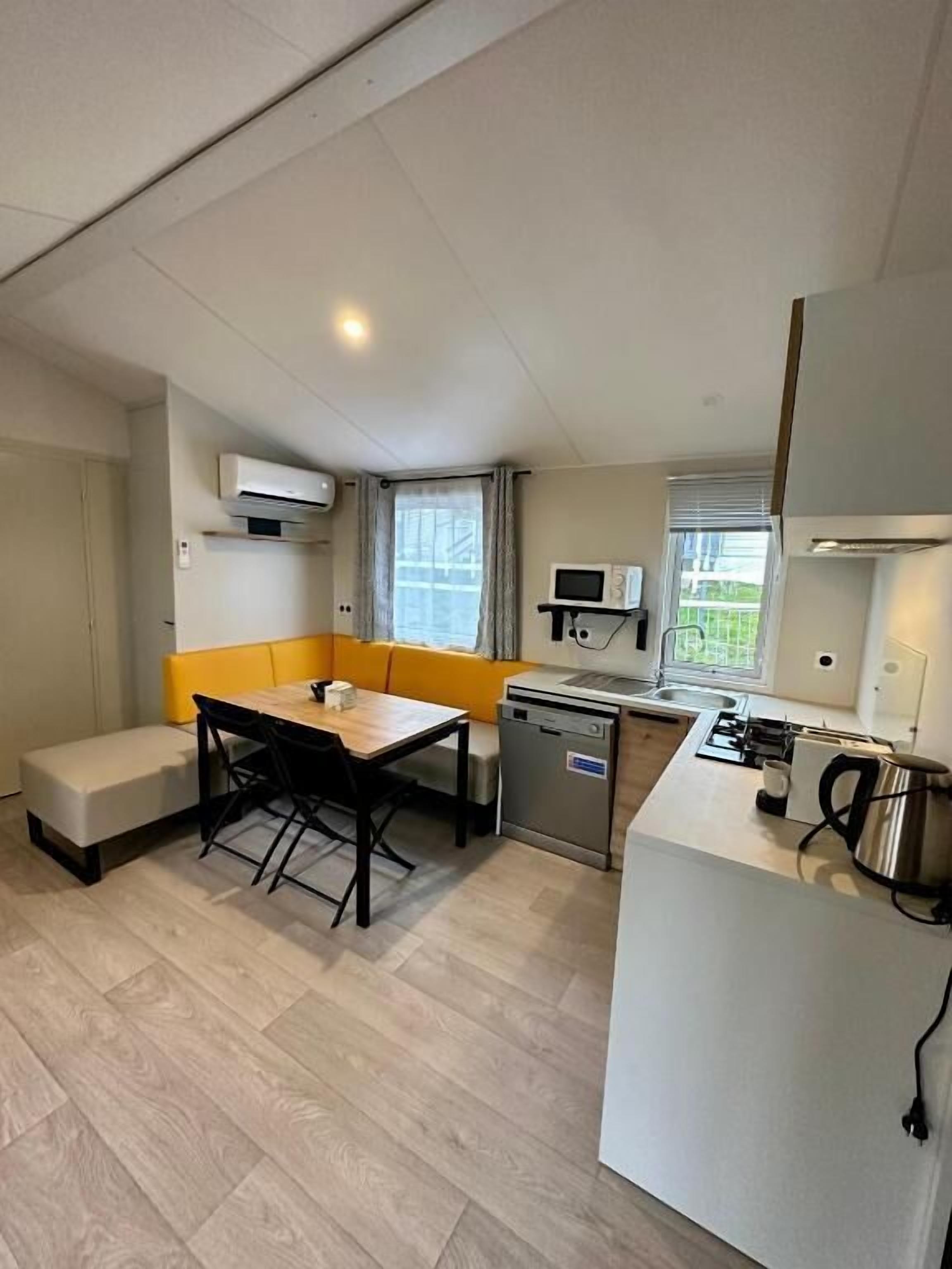 A compact kitchen with a dining area, including a table, chairs, and a bench.