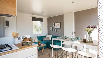 A modern kitchen with a dining area, a teal sofa, and a small table with chairs.