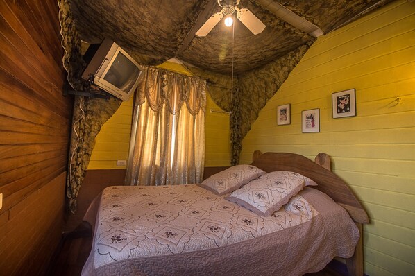A bedroom with a bed, a ceiling fan, a television, and a window with curtains. - Hotel Casa Antigua (Rio Segundo)