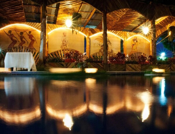 An indoor pool area with a table and chairs, surrounded by a covered seating area with a mural. - Hotel Casa Antigua (Rio Segundo)