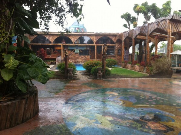 A courtyard with a mosaic floor, a pool, and a building with arched windows. - Hotel Casa Antigua (Rio Segundo)