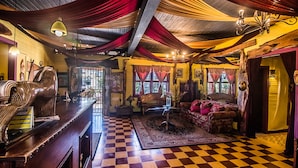 Een kamer met een geruite vloer, houten meubels en draperende stoffen aan het plafond.