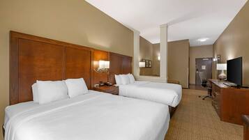 A hotel room with two beds, a desk, a chair, a TV, and a mirror.