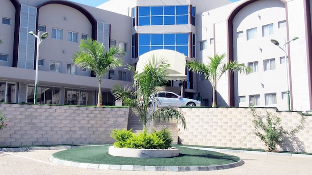 A hotel with a central atrium, multiple balconies, and a landscaped courtyard with palm trees. - The Matola Hotel (Matola)