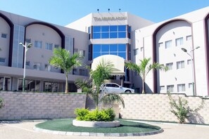 Un hôtel doté d’un atrium central, de nombreux balcons et d’une cour aménagée avec des palmiers.