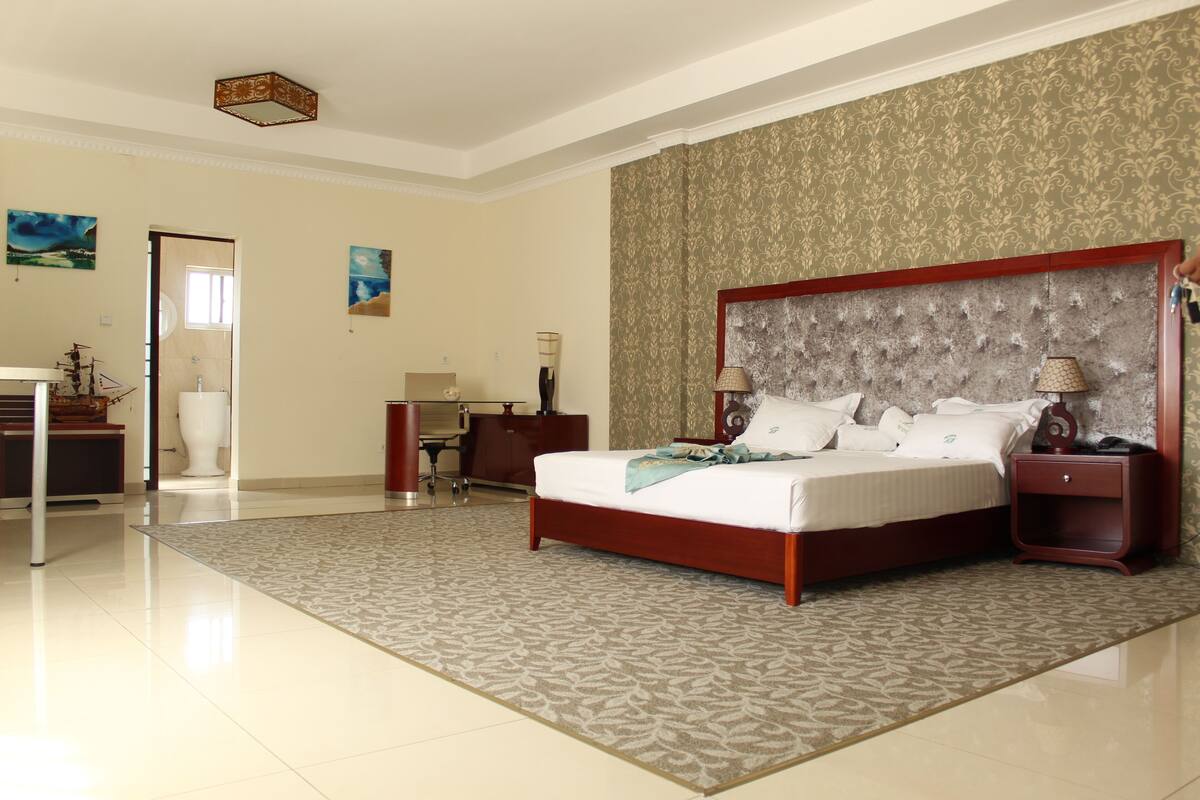 A spacious bedroom with a large bed, a desk, and a chair.
