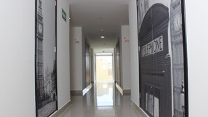 A corridor with a polished floor, a door labeled "Telephone," and a wall with a black and white image of a clock tower. - Urbainn Hotel (Veracruz)