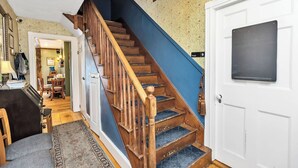 Un escalier avec des marches en bois et une rampe bleue menant à une porte blanche sur laquelle est fixé un tableau noir.
