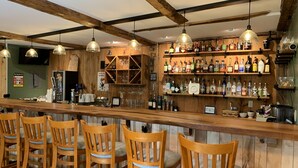Un bar avec des chaises en bois et des étagères remplies de bouteilles d’alcool.