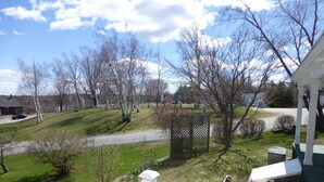 A residential area with a green lawn, a white fence, and a clear sky.