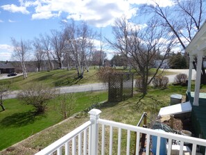 A residential area with a green lawn, a white fence, and a clear sky.