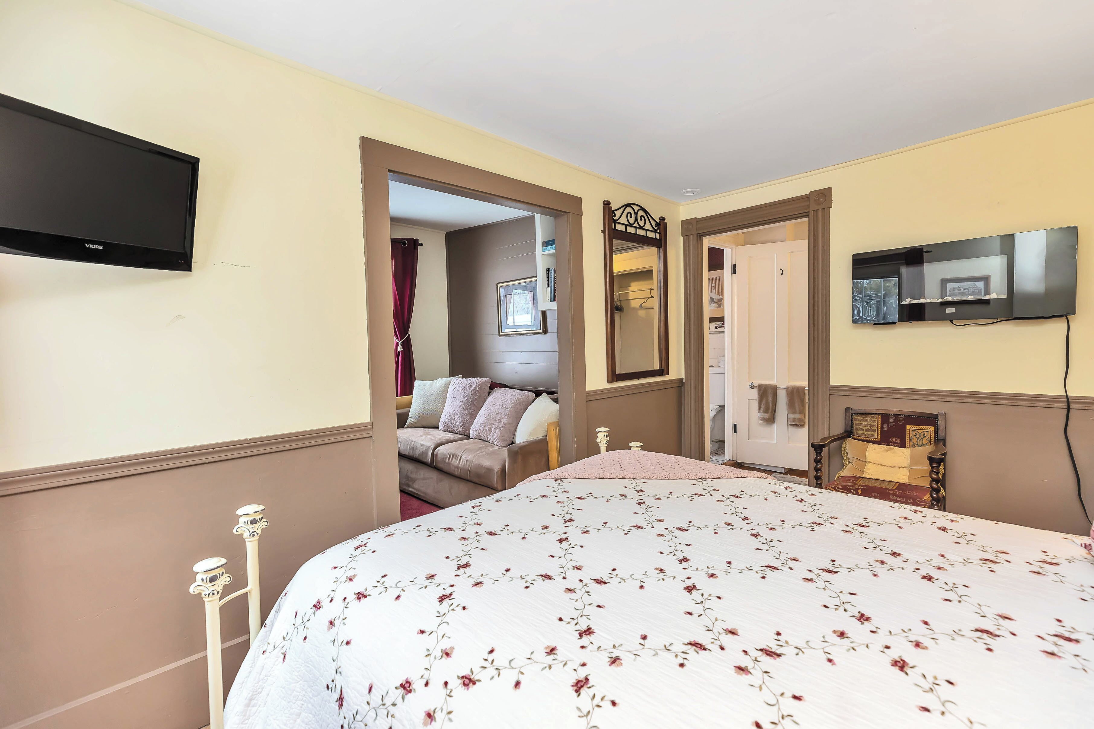 A hotel room with a bed, a TV mounted on the wall, and a door leading to a bathroom.