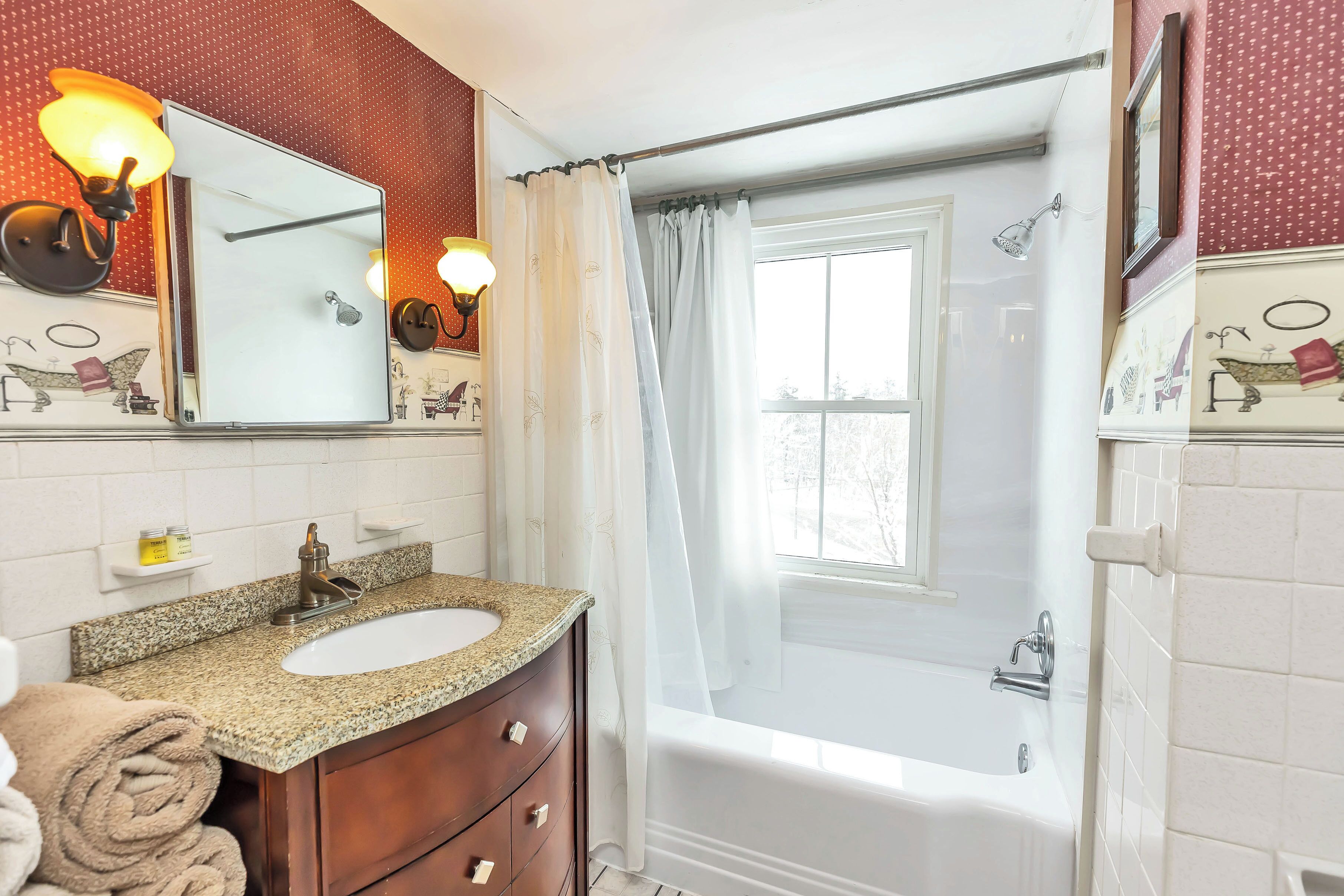 A bathroom with a sink, vanity, and bathtub.