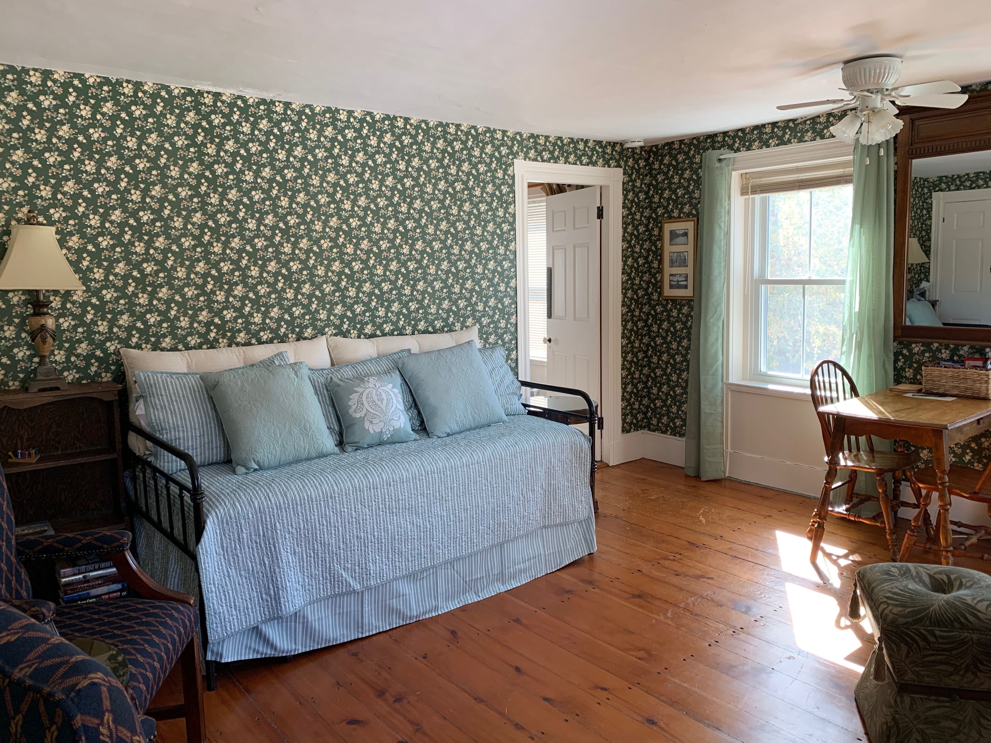 A room with a bed, a desk, a chair, a lamp, and a bookshelf.