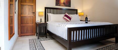 A bedroom with a wooden bed, a nightstand, a lamp, and a painting on the wall.