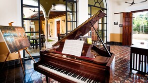 Un piano de cola en una habitación amplia con ventanas grandes, un comedor y vistas al exterior.