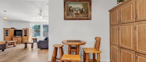 A wooden dining set with a table and chairs, a painting on the wall, and wooden cabinets.