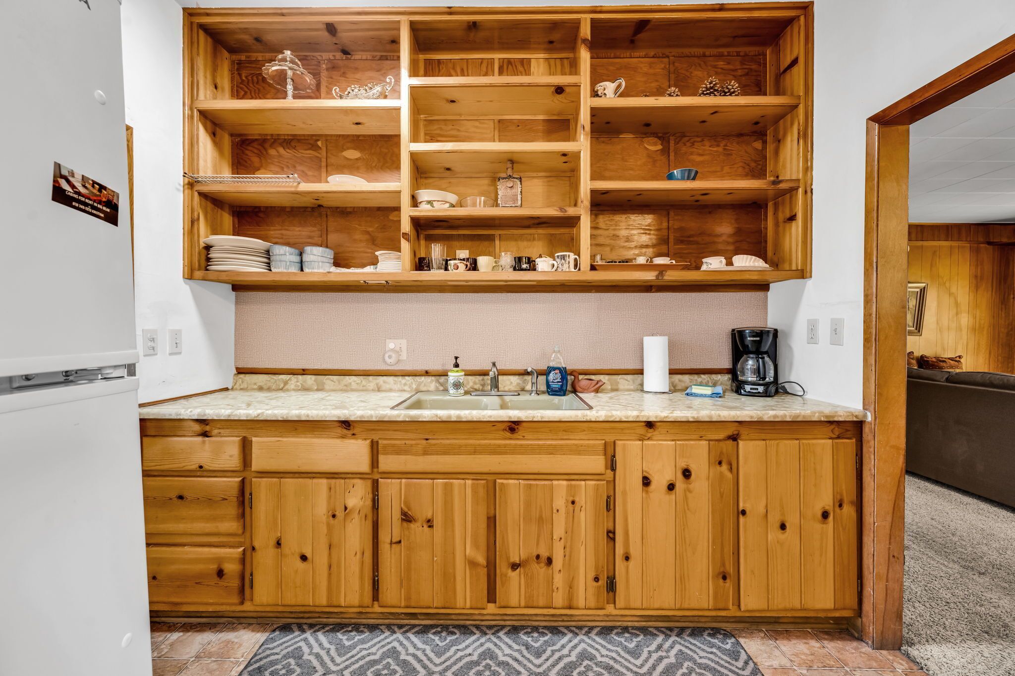 A kitchen with wooden cabinets, a marble countertop, and a built-in shelf unit.