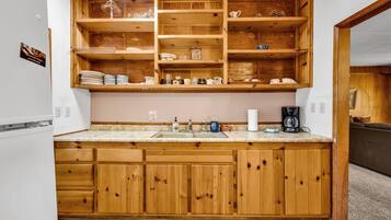 A kitchen with wooden cabinets, a marble countertop, and a built-in shelf unit.