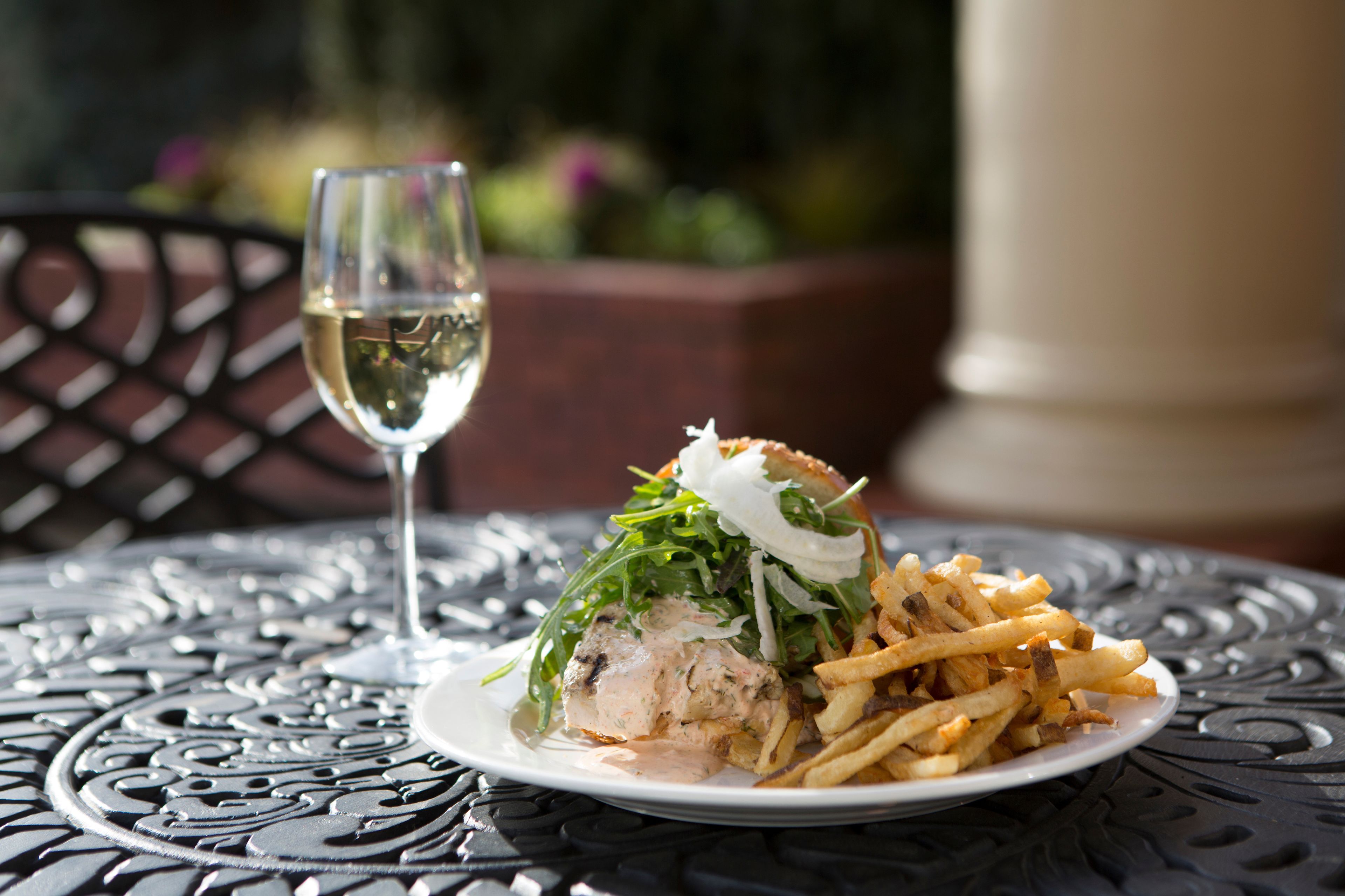 A plate of food with a sandwich and fries on a metal table.