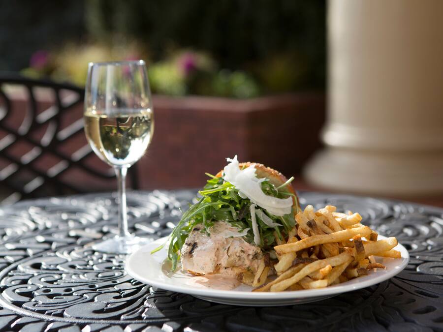 A plate of food with a sandwich and fries on a metal table.