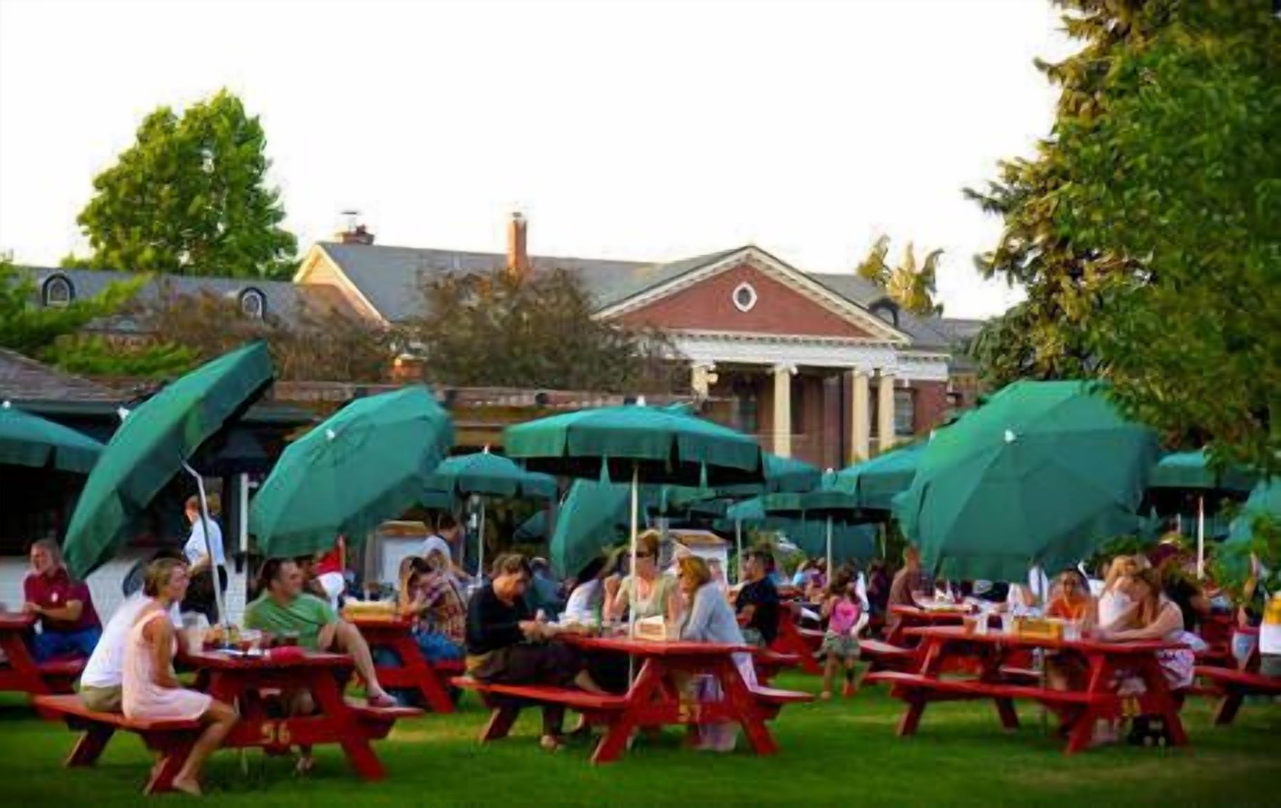 An outdoor seating area with red picnic tables and green umbrellas.