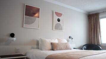 Habitación de hotel con cama, escritorio y dos lámparas fijadas a la pared.