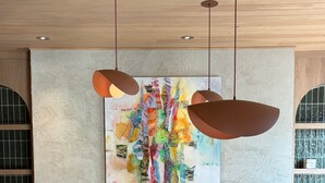 Una sala de estar moderna con chimenea, dos sillones, una mesa de centro redonda y un cuadro abstracto y colorido sobre la chimenea.