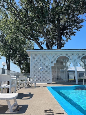 A poolside area with white chairs and a gazebo. - Auberge Le Parasol  (Saguenay)