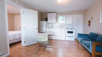 A compact living space with a kitchenette, a dining area, a bed, and a sofa.