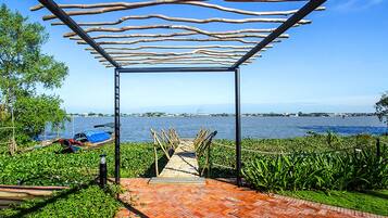 A wooden pathway leading to a covered area with a view of a body of water.