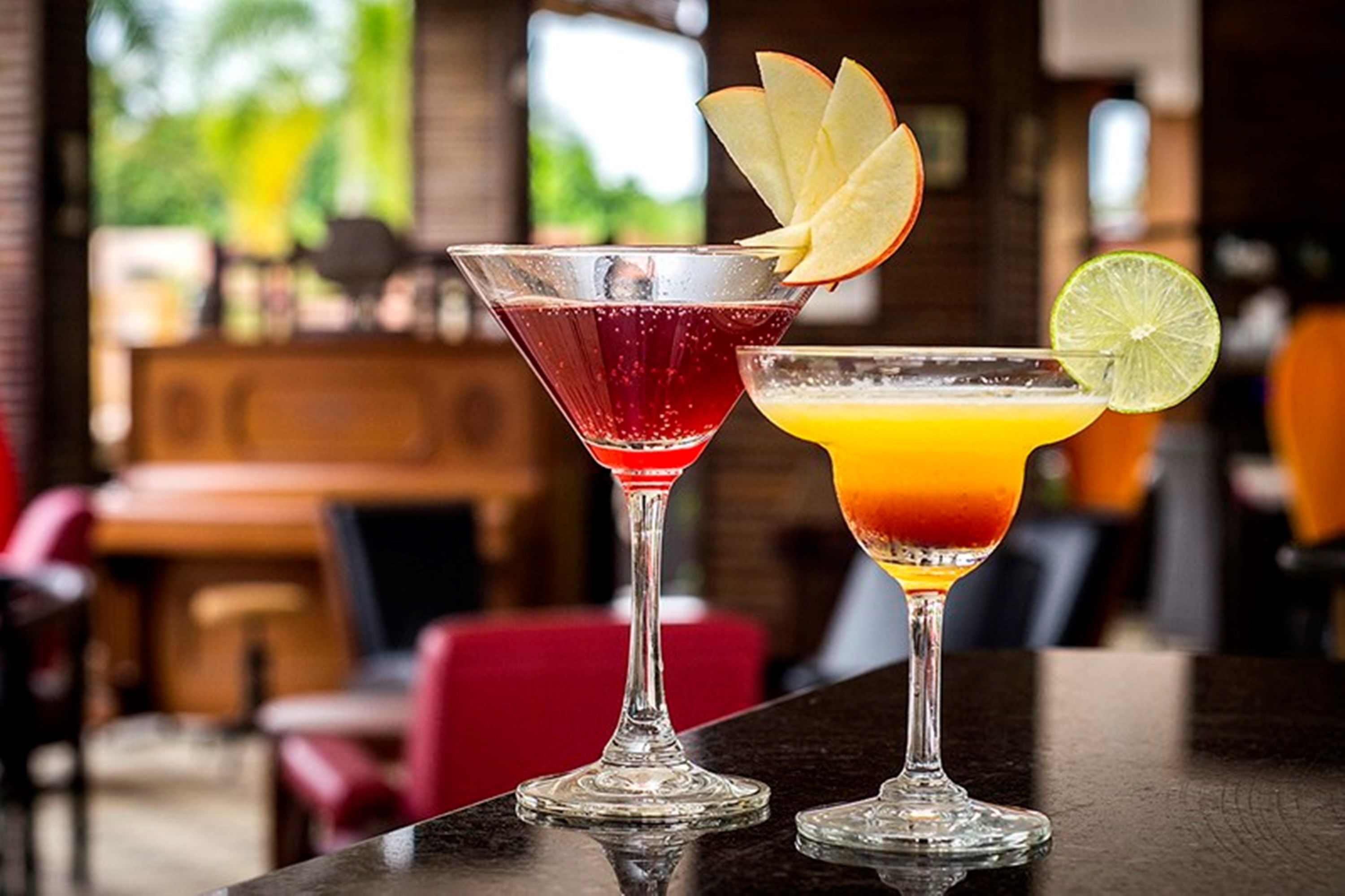 Two cocktails on a bar counter with a blurred background of a restaurant interior.