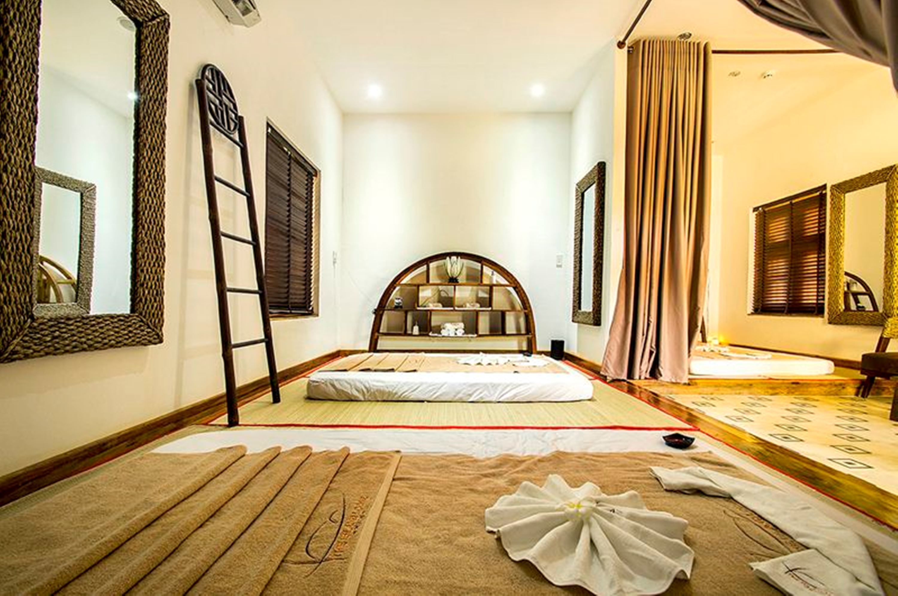 Ein Schlafzimmer mit einem Bett, einer Leiter, einem großen Spiegel und einer Futonliege.