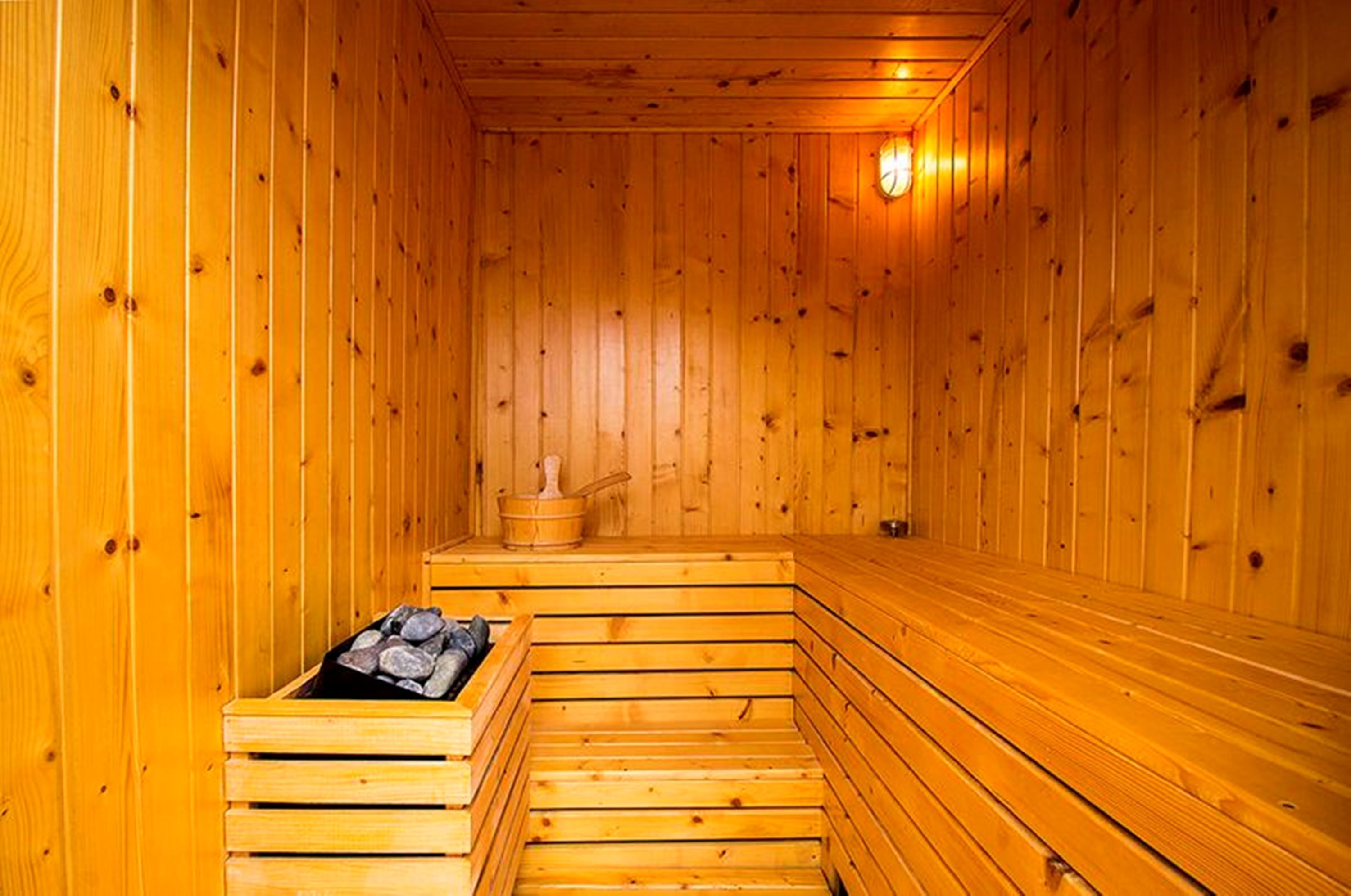 Eine Holzsauna mit Bänken und einem stein gefüllten Behälter.