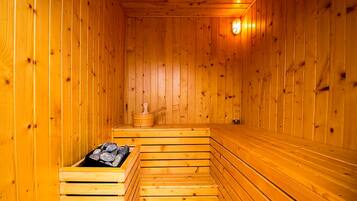 Eine Holzsauna mit Bänken und einem stein gefüllten Behälter.