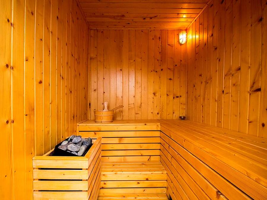 Eine Holzsauna mit Bänken und einem stein gefüllten Behälter.