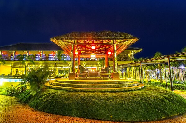A well-lit outdoor area with a circular seating arrangement, a covered pavilion, and a pool.