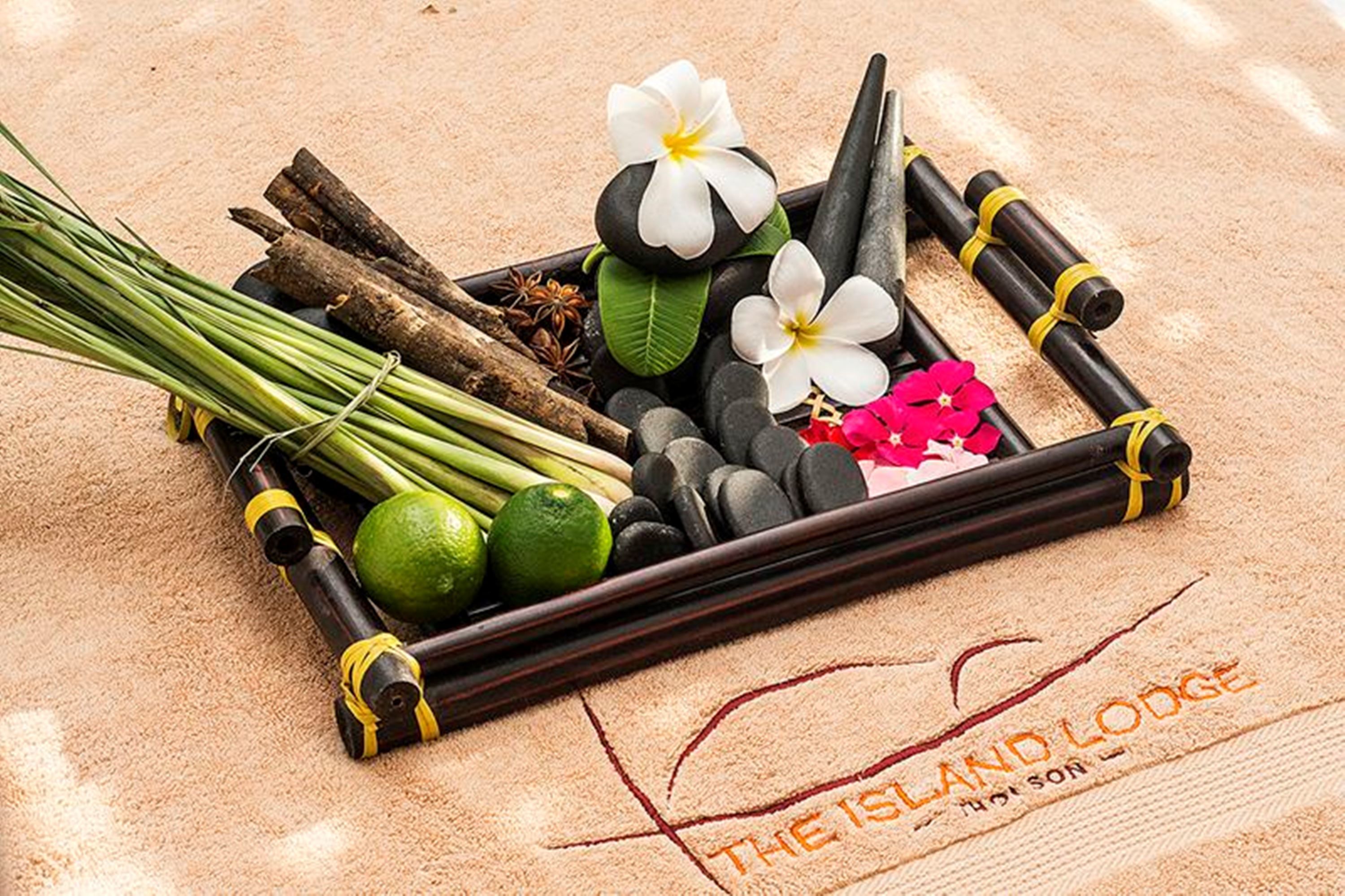 Una bandeja con elementos naturales como piedras, flores y hierbas, posiblemente para un ambiente de spa.