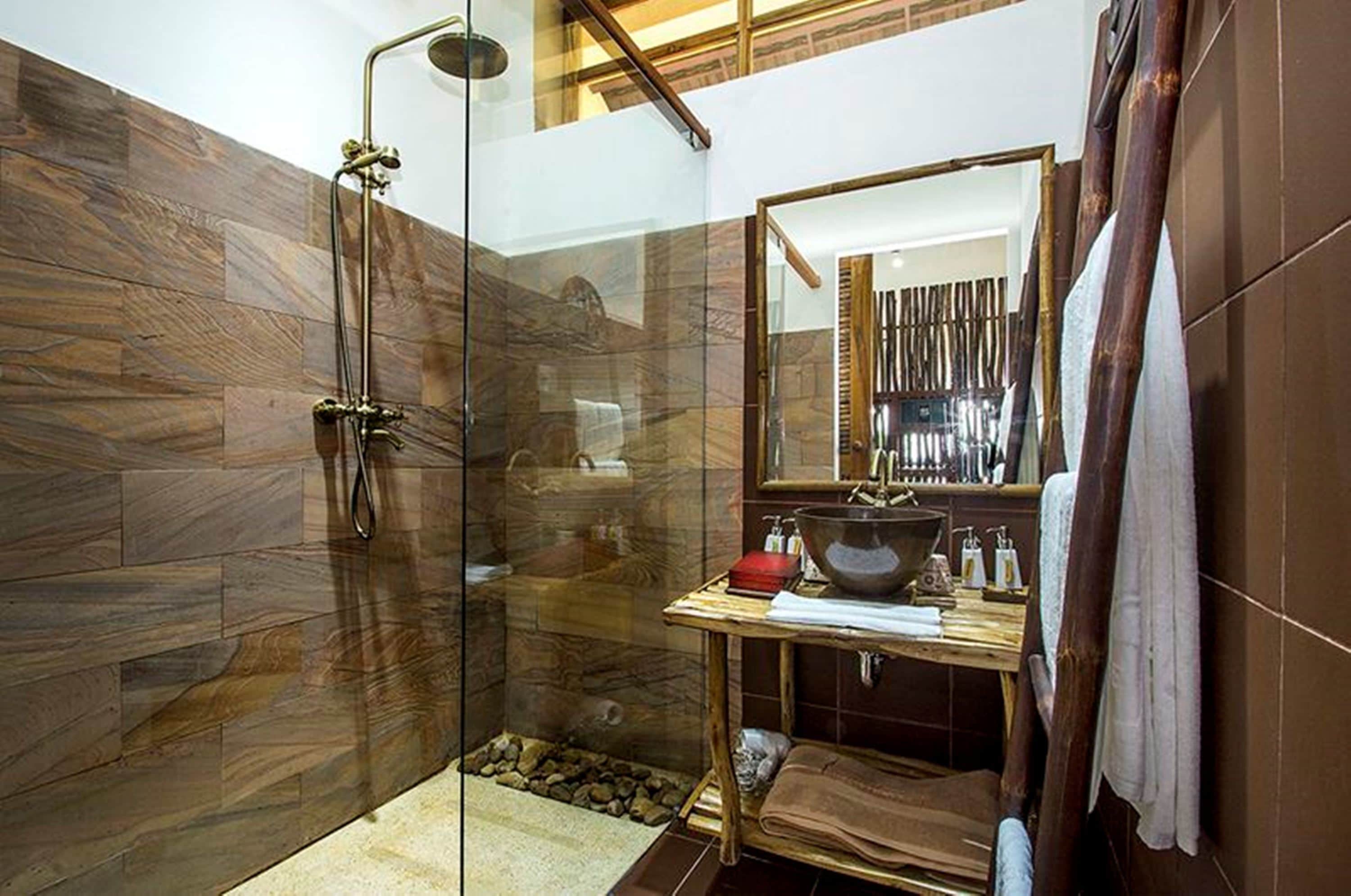 A modern bathroom with a glass shower enclosure, a wooden vanity, and a large mirror.