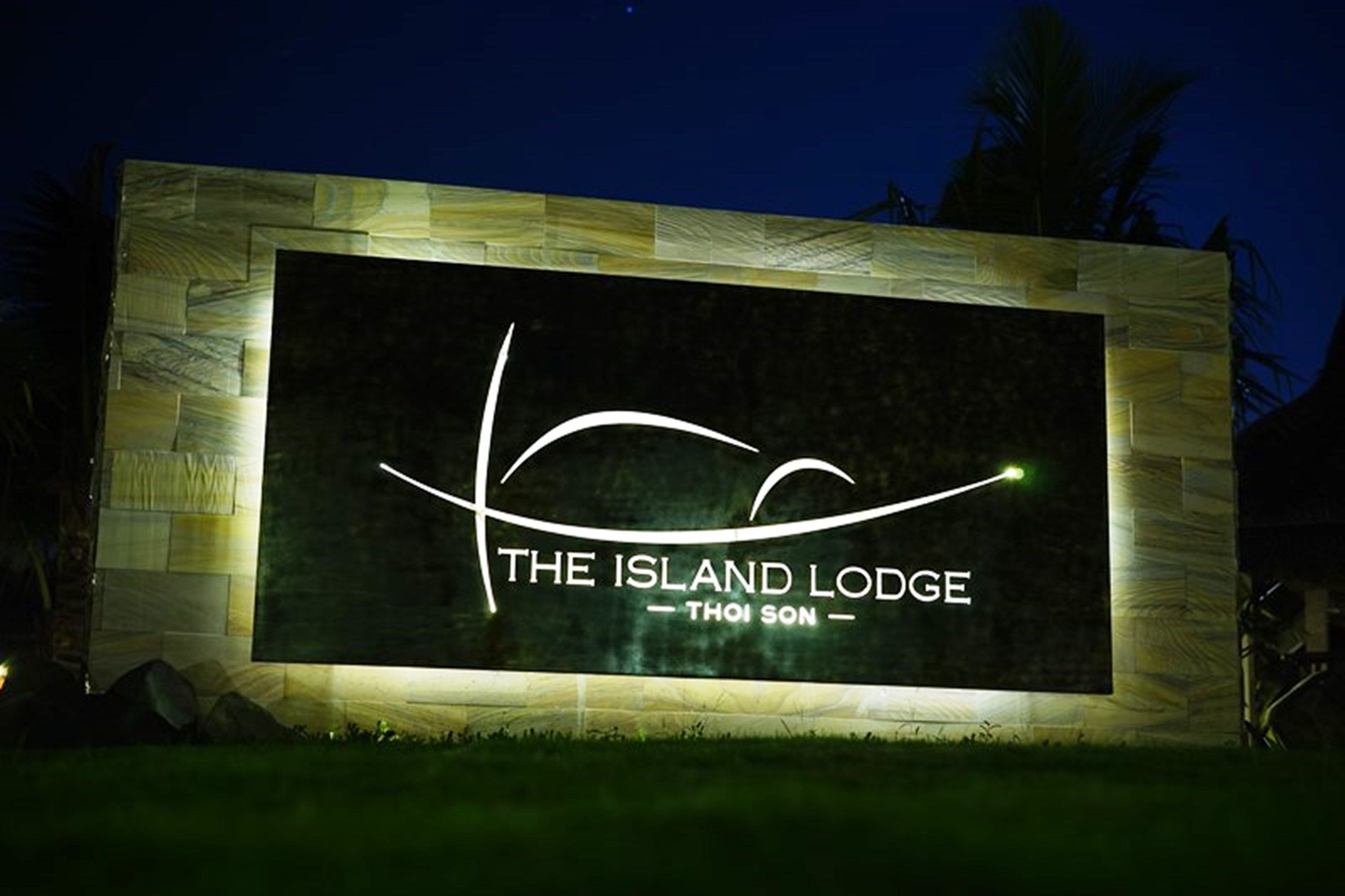 A sign for "The Island Lodge" with a stylized wave design and the name "Thoi Son" below it.