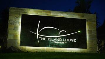 A sign for "The Island Lodge" with a stylized wave design and the name "Thoi Son" below it.